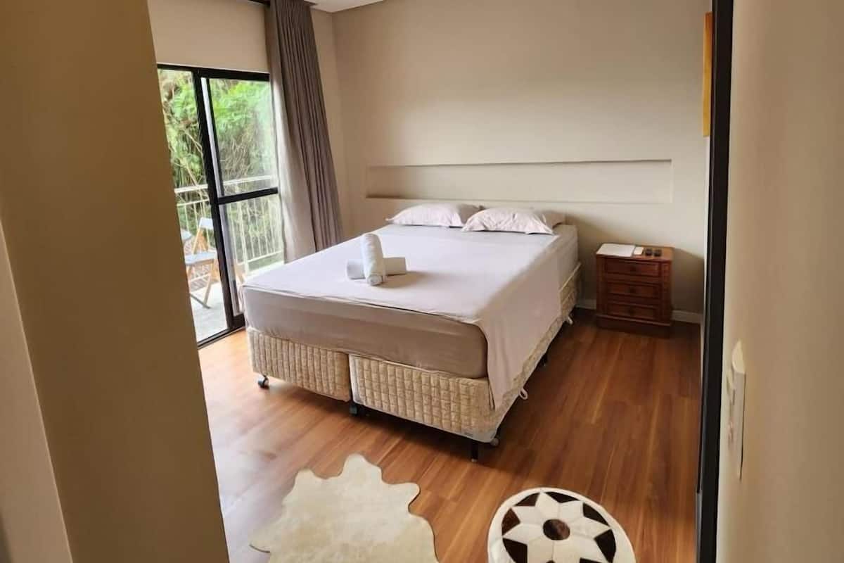 Ein modernes Schlafzimmer mit einem großen Bett, einem Nachttisch und Blick ins Freie.