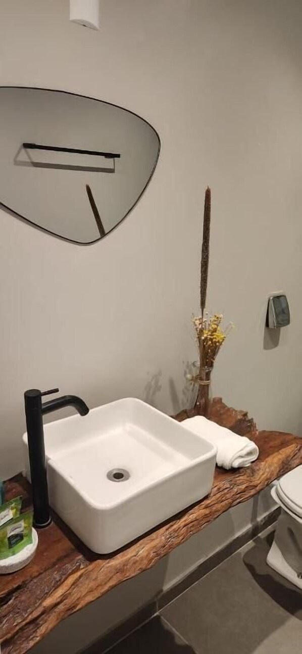 Une salle de bain avec un lavabo blanc, un robinet noir et un meuble-lavabo en bois.
