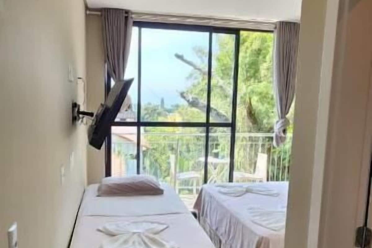 Ein Hotelzimmer mit zwei Betten, einem großen Fenster und Holzboden.