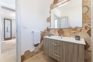 A bathroom with a white vanity, a mirror, and a tiled backsplash. - Villa Miravalle - Salve (Salve)