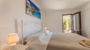 A bedroom with a bed, bedside lamps, a painting, and a view of the outdoors. - Villa Miravalle - Salve (Salve)