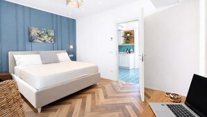 A modern bedroom with a bed, a laptop, and a view into the kitchen. - AMORE RENTALS - Apartment Seapearl Sorrento with Sea View, Near the Beach (Sorrento)