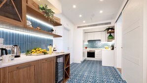 A modern kitchen with wooden cabinets, a white countertop, and blue patterned flooring. - AMORE RENTALS - Apartment Seapearl Sorrento with Sea View, Near the Beach (Sorrento)