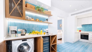 A modern kitchen with a washing machine, a coffee maker, and a fruit bowl on the counter. - AMORE RENTALS - Apartment Seapearl Sorrento with Sea View, Near the Beach (Sorrento)