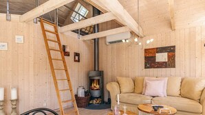 Un cuarto acogedor con detalles de madera, un sofá, una escalera, una chimenea y un candelabro.