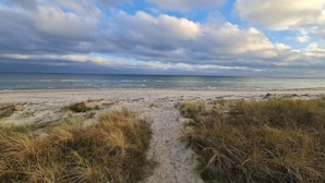 Un sendero bordeando la playa que lleva al océano bajo cielos nublados.