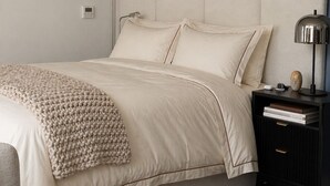A bedroom with a bed, bedside table, lamp, and a wall-mounted thermostat. - Cozy 1-bedroom apartment with AC in vibrant Seattle neighborhood (Seattle)