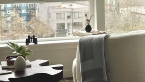 A room with a large window, a chair, a small table with a plant, and a vase. - Cozy 1-bedroom apartment with AC in vibrant Seattle neighborhood (Seattle)