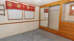 A room with a wooden dresser, a mirror, and a window with a red floral curtain.