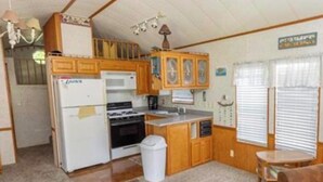 A compact kitchen with a refrigerator, stove, and wooden cabinets.