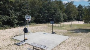 An outdoor basketball court with a bench and a basketball hoop.