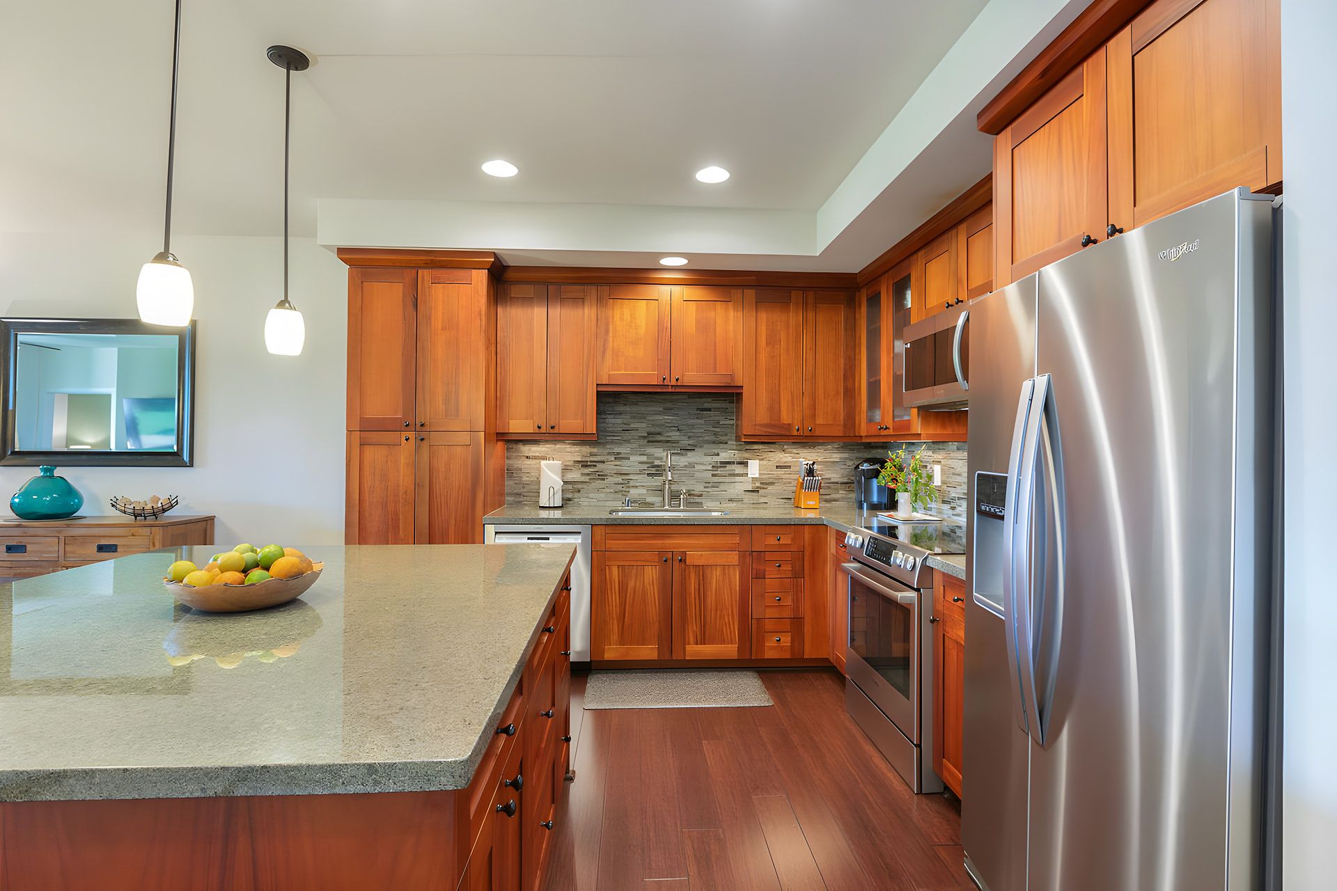 A modern kitchen with wooden cabinets, a stainless steel refrigerator, and a granite countertop.