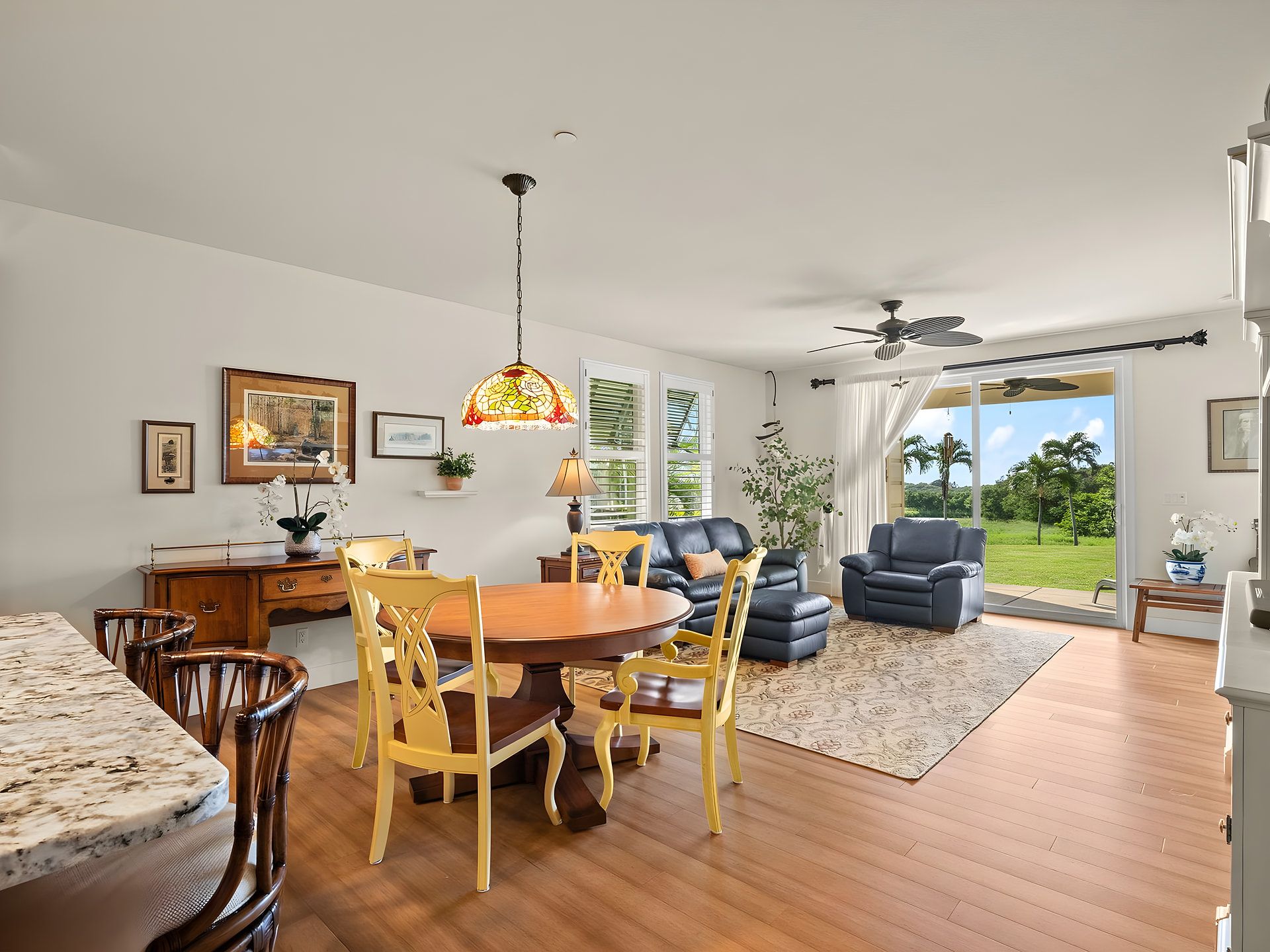 A spacious living room with a dining area, a ceiling fan, and a view of the outdoors.