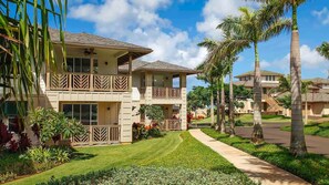 A two-story hotel with a balcony, surrounded by palm trees and a well-maintained lawn. - Pili Mai - 5BR Townhomes - Sleeps 14 (Koloa)