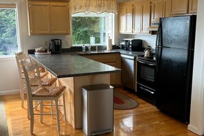 Una cocina con armarios de madera, un refrigerador negro, una cafetera y un hervidor.