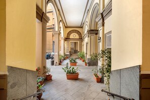 A corridor with tiled flooring, potted plants, and a staircase leading to an upper level. - Room 'Camera Matrimoniale Standard' with Wi-Fi and Air Conditioning (Napoli)