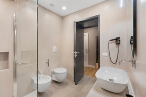 A modern bathroom with a glass shower enclosure, a bidet, a sink, and a hairdryer mounted on the wall. - Room 'Camera Tripla Superior' with Balcony, Wi-Fi and Air Conditioning (Napoli)