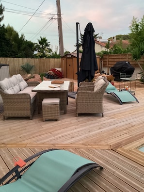 A patio with wicker furniture, a table, and a grill.