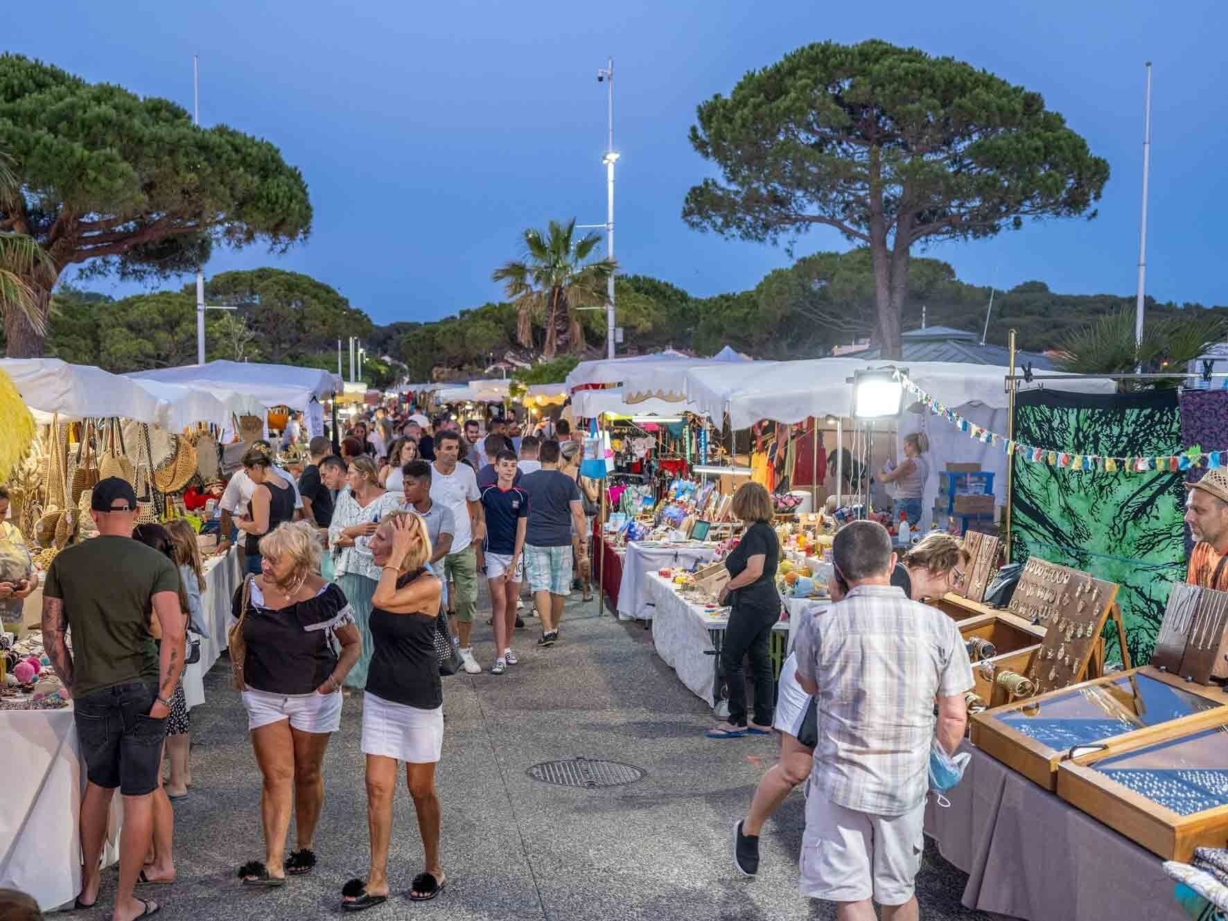 An outdoor market with various stalls and people browsing.
