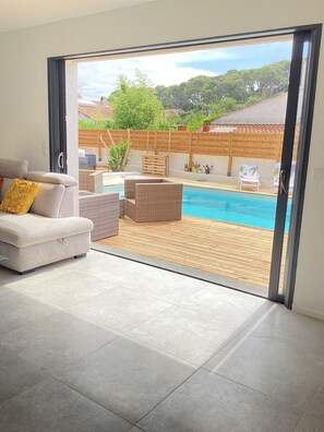 Un salon moderne avec un canapé, une piscine et une terrasse en bois.