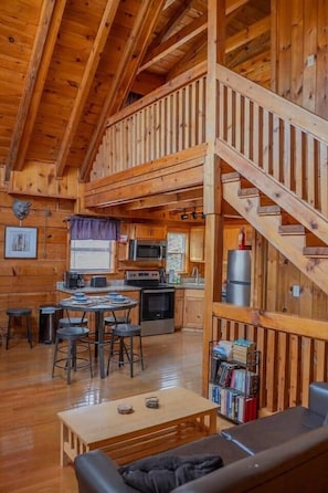 Ein Holzblockhaus-Interieur mit Küche, Essbereich und einer Treppe.