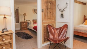 Una camera da letto con un letto, un armadio in legno, una poltrona in pelle, una lampada e una decorazione con corna di cervo.