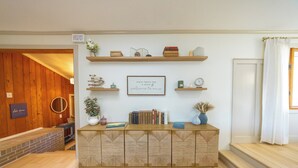 Een kamer met een houten vloer, een ingebouwde boekenkast, een lijst met een citaat aan de muur en een trap naar een hoger niveau.
