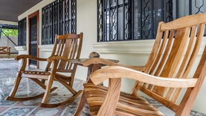 Une chaise à bascule en bois et une chaise en bois, avec une table devant un bâtiment dont les fenêtres sont grillagées.