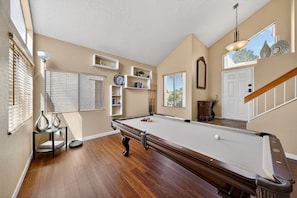 A pool table in a room with wooden flooring, a staircase, and a door. - Cozy 3BR Retreat w/ Spa in Green Valley Area (Henderson)