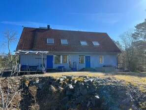 Een woonhuis met twee verdiepingen, een schuin dak, een voortuin en een fundering van natuursteen.