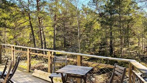 A wooden deck with a table and chairs, surrounded by a wooden railing, overlooking a forested area. - 4 Star Holiday Home in Runmaro (Runmaro)