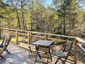 A wooden deck with a table and chairs, surrounded by a wooden railing, overlooking a forested area. - 4 Star Holiday Home in Runmaro (Runmaro)