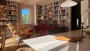 A spacious room with a large white table, multiple bookshelves filled with books, wicker chairs, and a large window allowing natural light. - 4 Star Holiday Home in Runmaro (Runmaro)