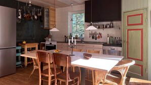 A modern kitchen with wooden cabinets, a dining area with wicker chairs, and a large window providing natural light. - 4 Star Holiday Home in Runmaro (Runmaro)
