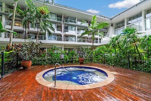 A hotel with a rooftop pool surrounded by lush greenery and a multi-story building with balconies. - Drift into Paradise: Exceptional Resort Living (Palm Cove)