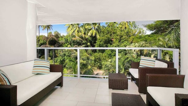 A balcony with wicker furniture and a view of lush greenery. - Drift into Paradise: Exceptional Resort Living (Palm Cove)