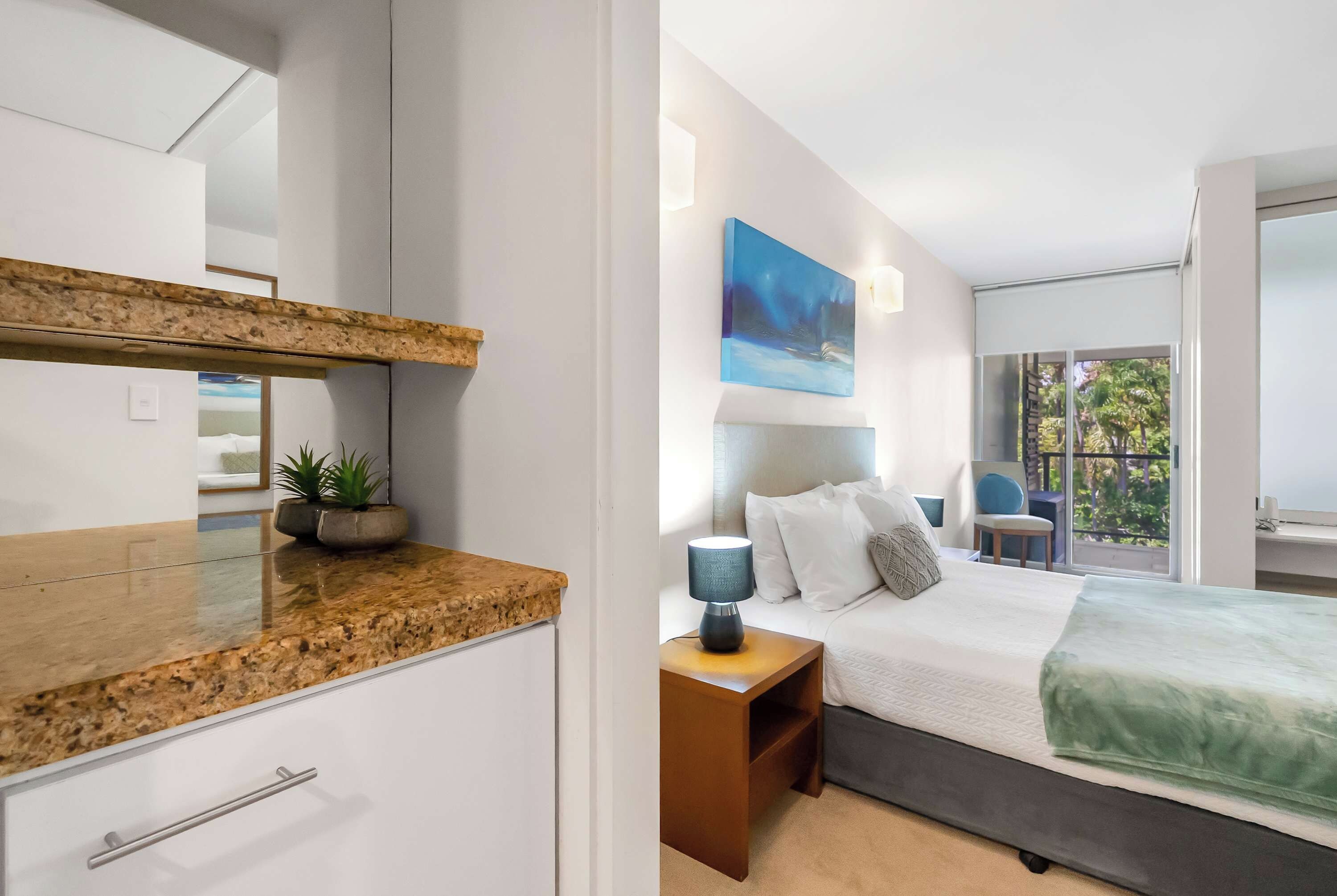 A modern bedroom with a bed, nightstand, and a view of the outdoors.