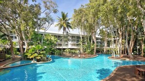 A swimming pool surrounded by trees and a building with balconies. - Drift into Paradise: Exceptional Resort Living (Palm Cove)