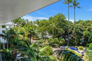 Blick auf eine Wohngegend mit hohen Palmen, geparkten Autos und blauem Himmel.