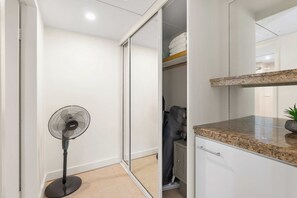 Une salle de bain moderne dotée d’une douche à parois de verre, d’un ventilateur sur pied et d’un comptoir en granit.