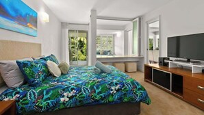 A modern bedroom with a bed, a TV, and a balcony with a view of greenery. - Drift into Paradise: Exceptional Resort Living (Palm Cove)