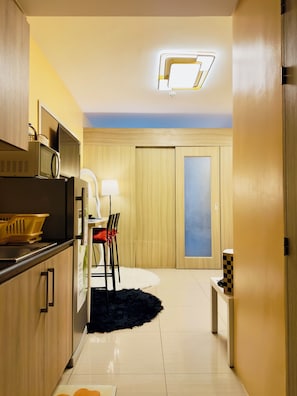 Eine moderne Küche mit Mikrowelle, Kühlschrank und Essecke mit Stuhl und Tisch.