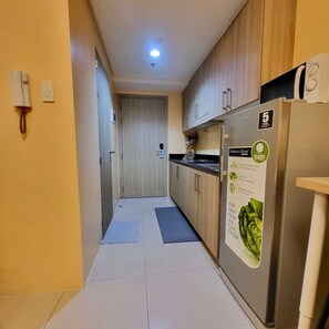 Eine schmale Küche mit Holzausstattung, einem Edelstahlkühlschrank und einem gefliesten Boden.