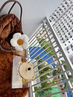 Blick von einem Balkon mit einer gewebten Matte, einer weißen Blume und einer braunen Tasche.