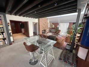 A spacious living area with a glass-top dining table, leather chairs, a brick fireplace, and a large window. - Cosy American Style apartment (Liverpool)