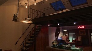 Un espacio habitable tipo loft con una escalera, un sofá, una mesa y un cartel de Coca-Cola.