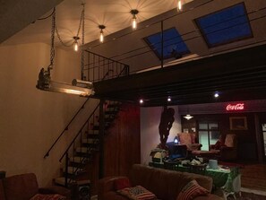 A loft-style living space with a staircase, a sofa, a table, and a Coca-Cola sign. - Cosy American Style apartment (Liverpool)