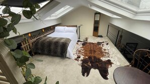 Una habitación con techos altos, una cama, un perro y un gran cuero de animal en el suelo.