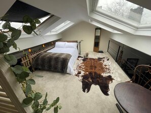 A high-ceilinged room with a bed, a dog, and a large animal hide on the floor. - Cosy American Style apartment (Liverpool)
