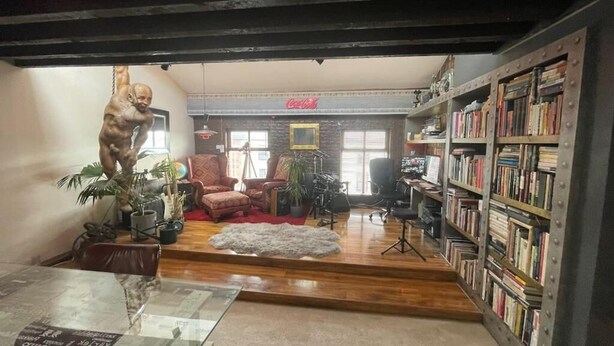 Una habitación con una mesa de vidrio, un sofá, una estantería y una estatua.